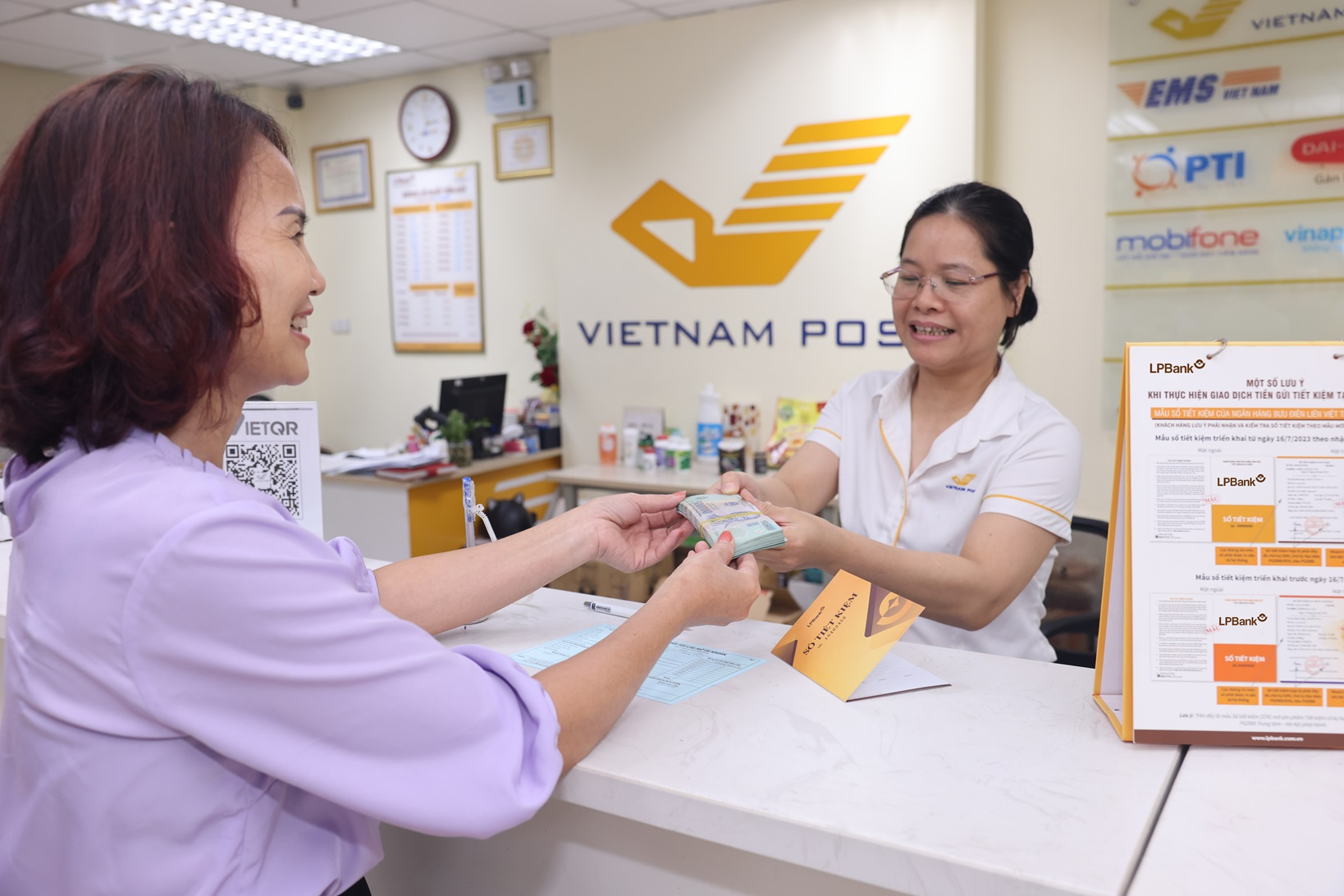 Giao dịch viên hỗ trợ khách hàng gửi tiết kiệm tại quầy